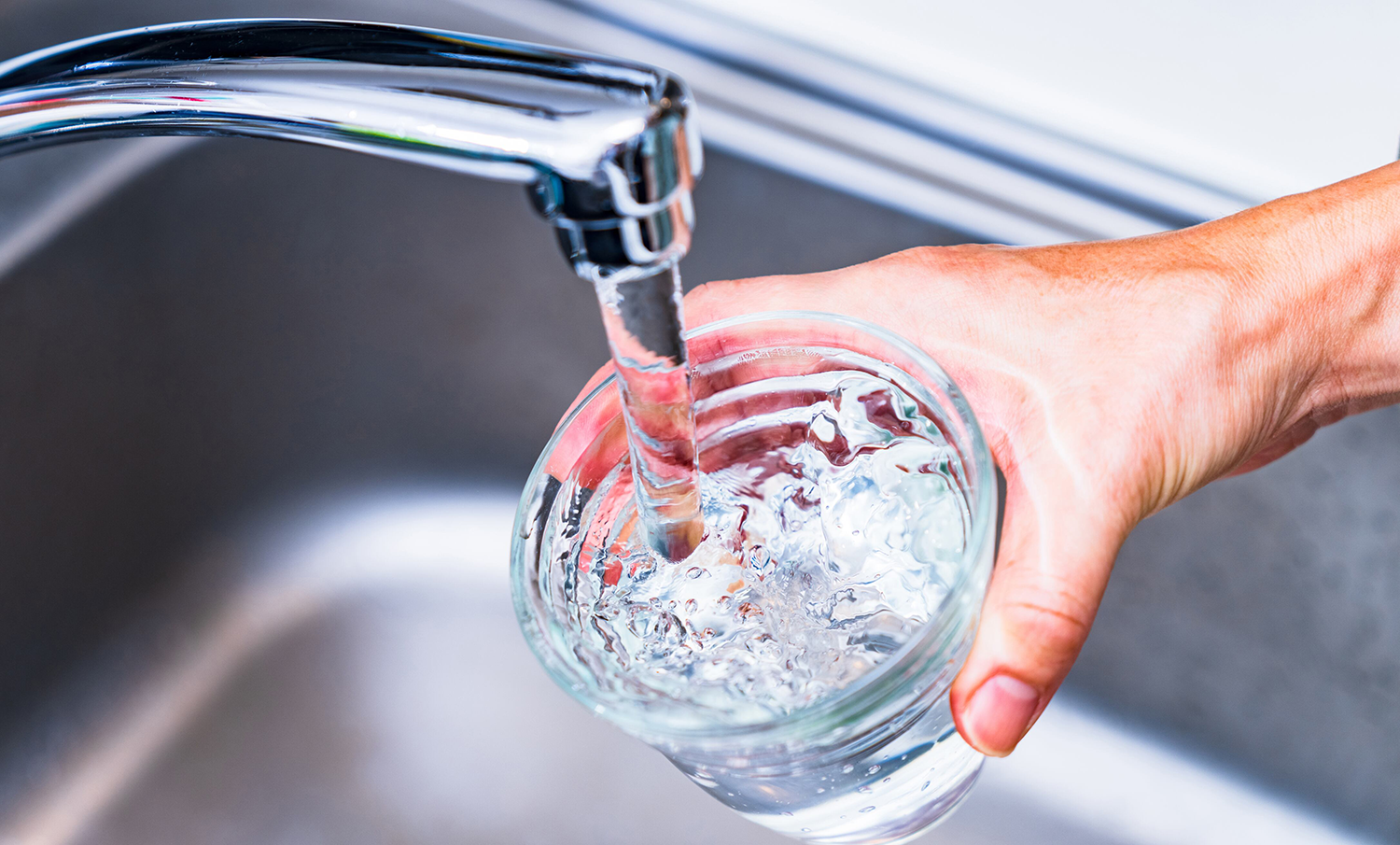 Llenando un vaso de agua en el grifo de la cocina