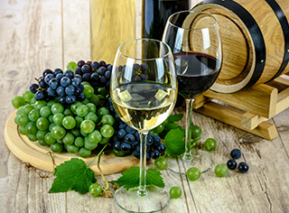 Copa de vino blanco y copa de vino tinto, con un plato de uvas