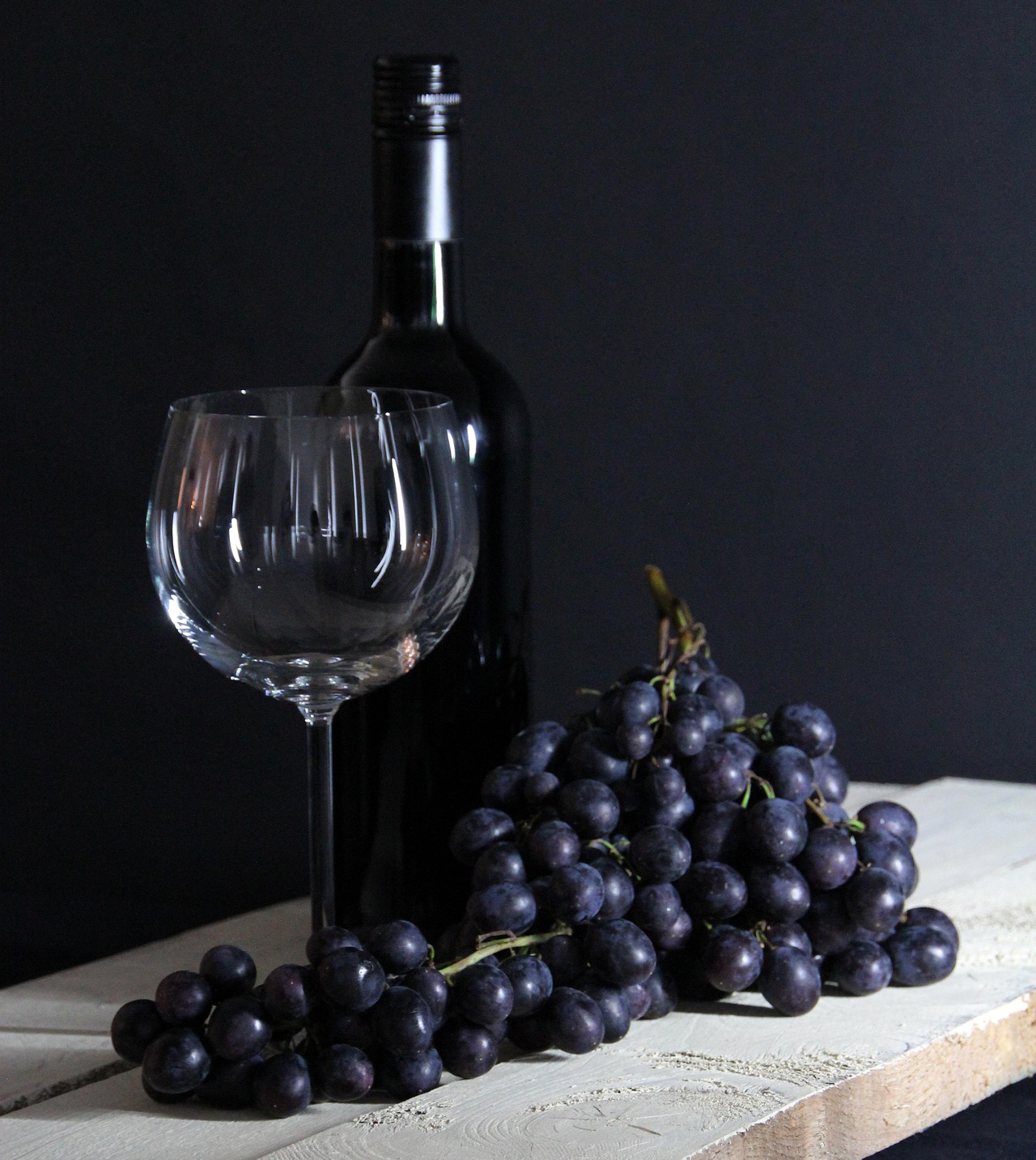 Botella de vino, con una copa y uvas delante